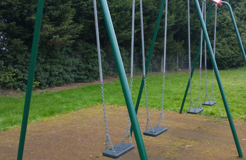A side on view of a set of red and blue swings
