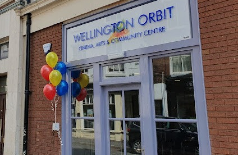 Frontage of the Orbit building. There are multi-coloured balloons to the left of the door.