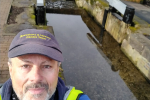 Cllr Tim Nelson in hi-vis and cap standing in front of Meretown Lock