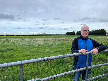 Phil Loughlin standing behind a gate overlooking the fields next to Station Road in The Humbers