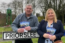 Cllrs Paul Thomas and Rachael Tyrell leaning on a Priorslee road sign